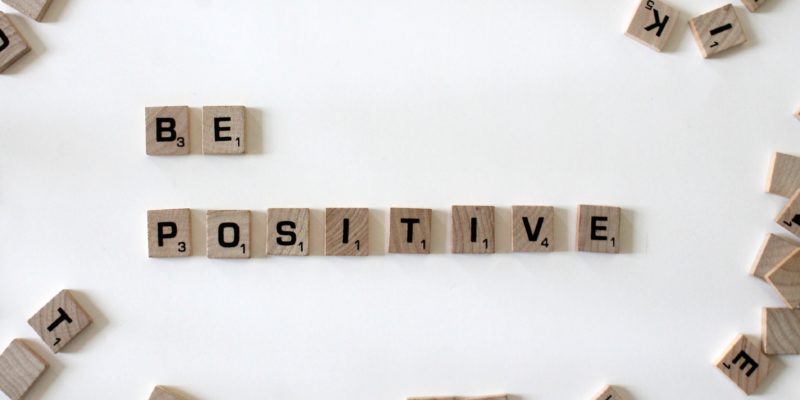 Be positive spelled out with scrabble letters on a white table