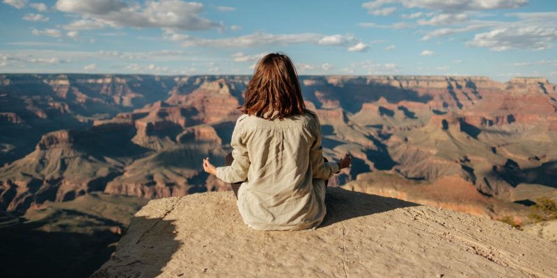 woman seated on the ground overlooking the grand canyon