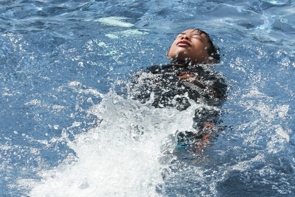Child laying on their back and swimming in a pool