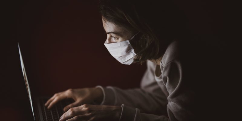 Woman wearing a mask in front of a laptop