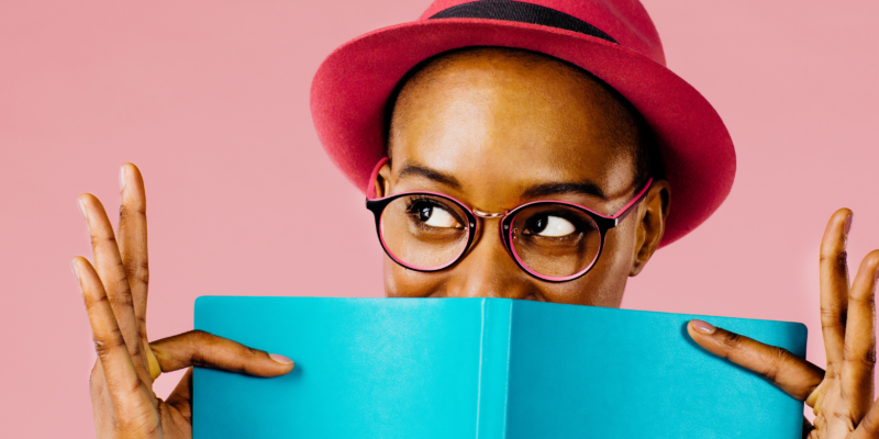 woman with glasses and a hat holding a book, colors are bight and cheerful