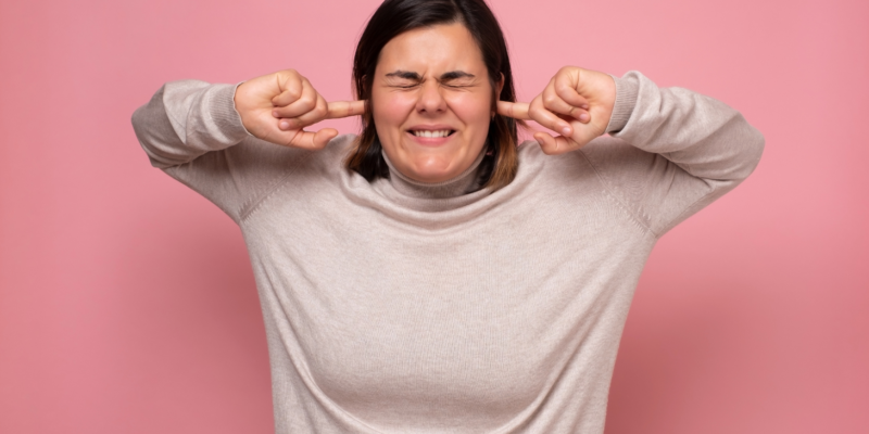 Woman avoiding seeing, hearing or doing something by having her eyes closed, fingers in her ears and mouth closed