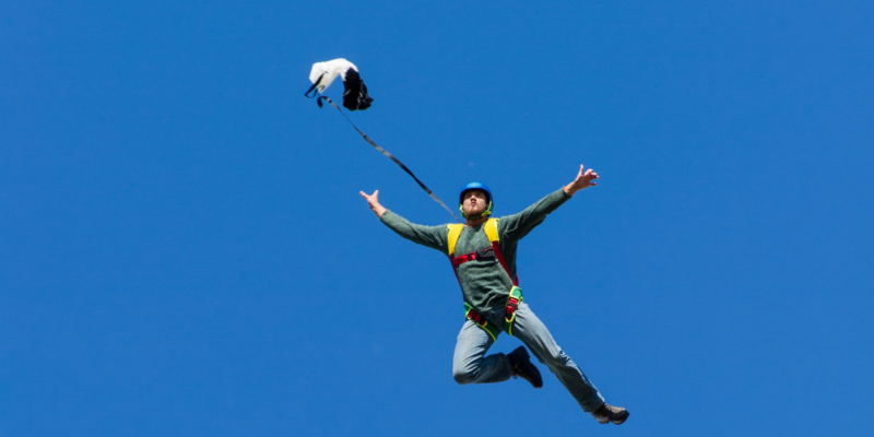 Man jumping in tree pose with a parachute on